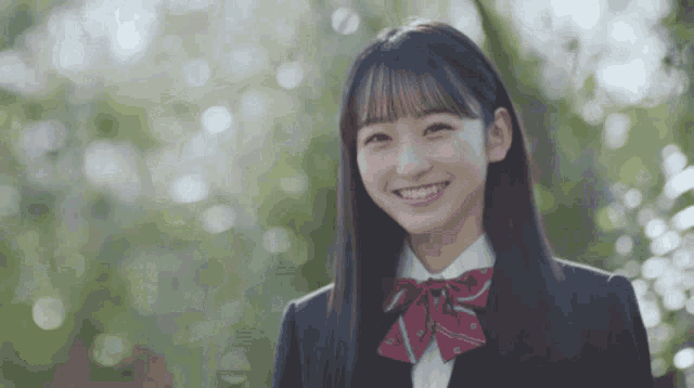 a girl with long hair and a red bow tie smiles