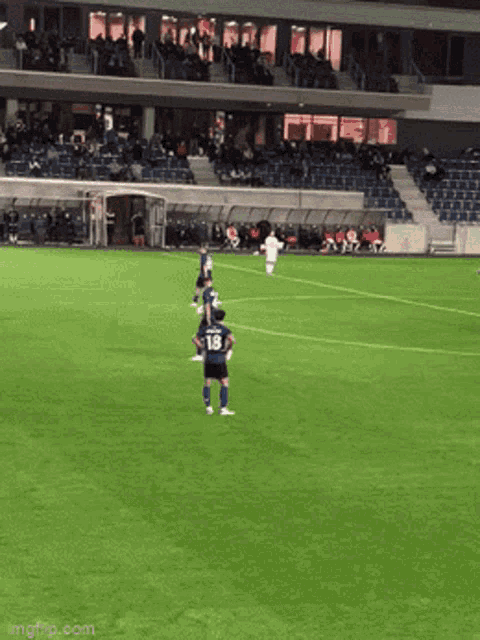 a soccer player with the number 18 on his back stands on the field