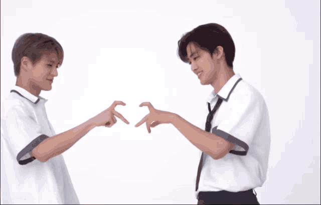 two young men in white shirts and ties are making a heart with their hands