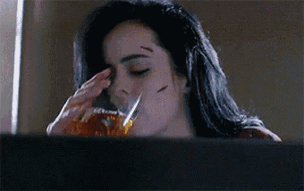 a woman is drinking a glass of whiskey while looking out of a window .