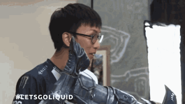 a man wearing glasses is holding a statue of a shark and talking on a cell phone .