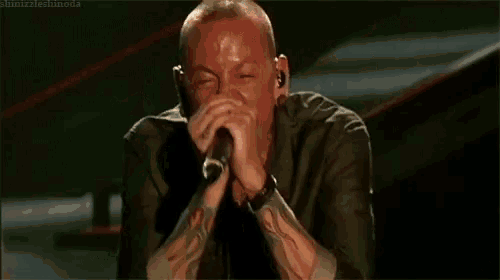 a man is singing into a microphone while sitting on a stage .