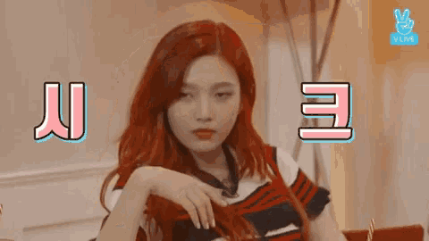 a woman with red hair is sitting at a table with a sign that says vlive