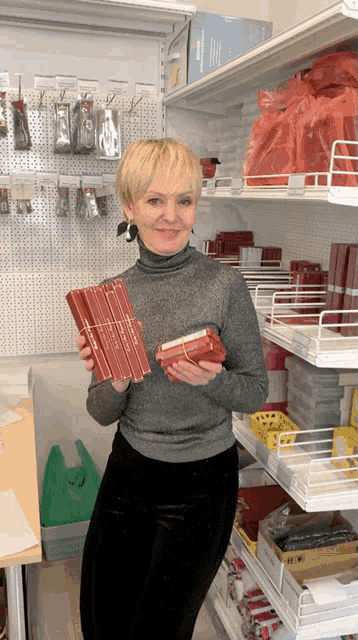 a woman in a store holds a stack of red pencils that say ' albrecht dürer '