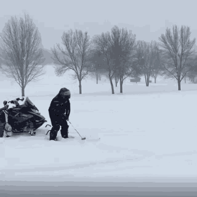 a snowmobile is parked in the snow and a person is playing golf