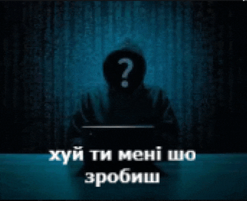 a man with a question mark on his face is sitting in front of a laptop .