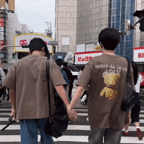 two people holding hands with one wearing a t-shirt that says acme de la vie
