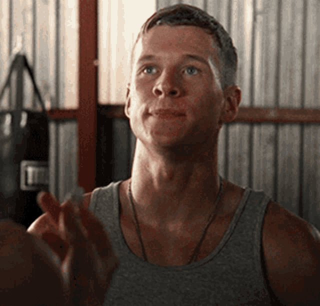 a man wearing a grey tank top is talking to another man