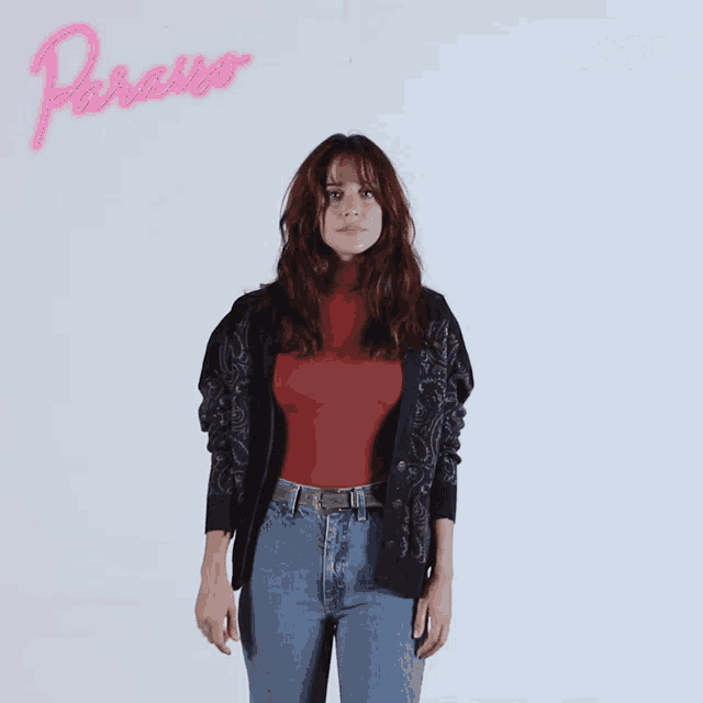 a woman is standing in front of a poster that says paraiso