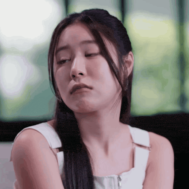 a woman in a white tank top is making a face