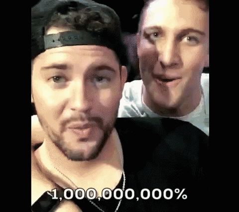 two men are standing next to each other and one of them is wearing a hat and the other is wearing a necklace .
