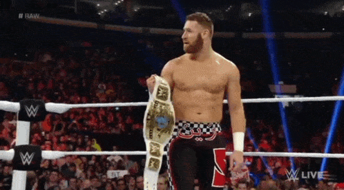 a man in a wrestling ring holding a belt that says raw on it