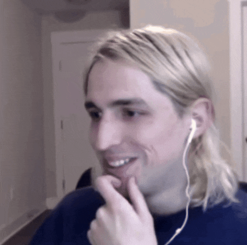 a man with long blonde hair is wearing ear buds