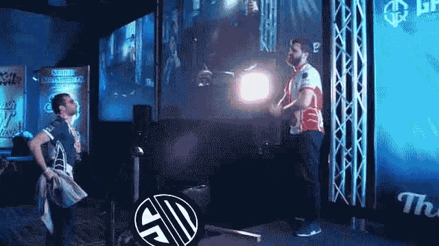 two men are standing in front of a large screen with the letters sd on it