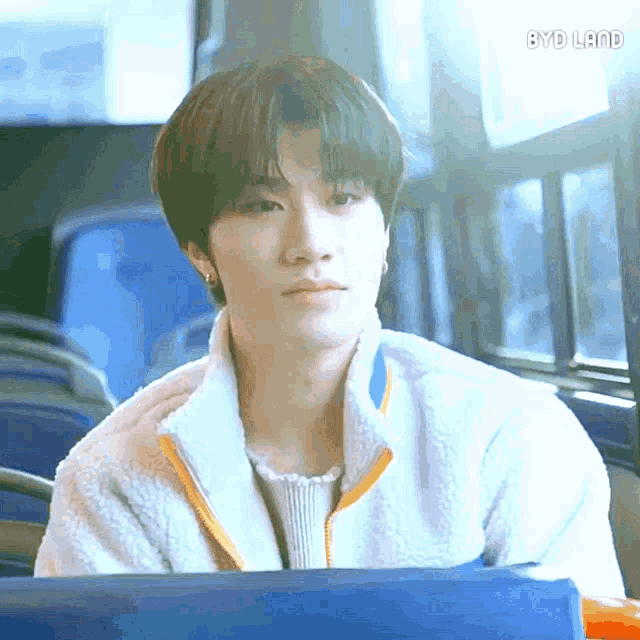 a young man sitting on a bus with byd land written on the bottom right corner