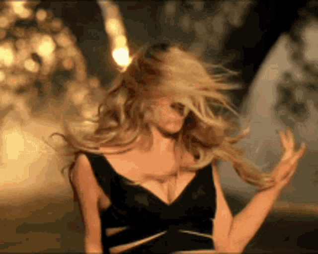 a woman in a black dress is dancing and her hair is blowing in the wind