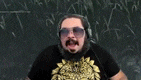 a man with a beard is wearing headphones and sunglasses and making a funny face .