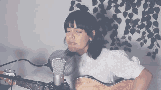 a woman is singing into a microphone while playing a guitar