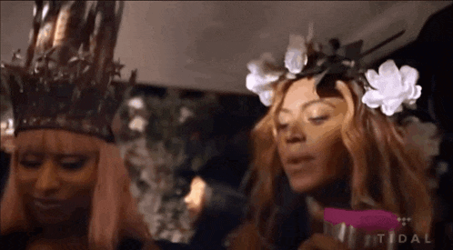 two women wearing crowns and flowers in their hair are standing next to each other and the word tidal is on the bottom right