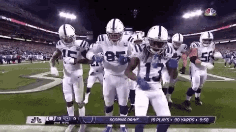 a group of indianapolis colts football players are dancing on the field .