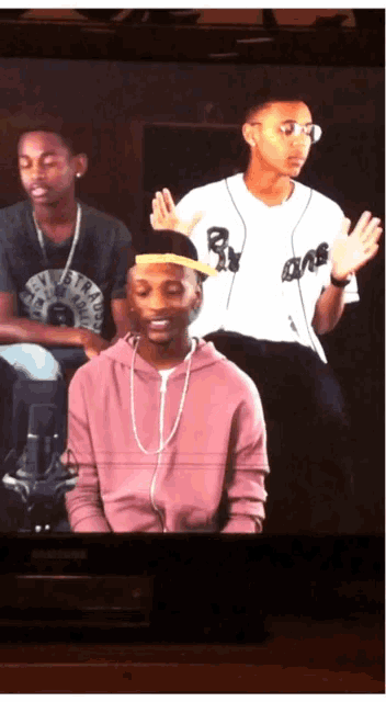 a man in a pink hoodie is sitting next to another man in a white shirt