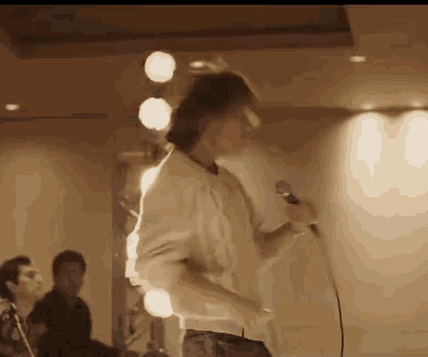 a man is singing into a microphone on a stage while dancing .