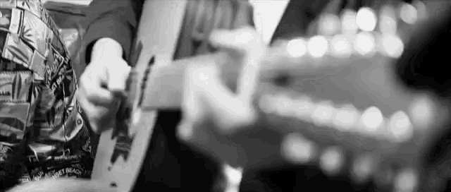 a black and white photo of a man playing a guitar .