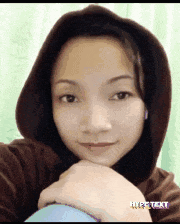 a woman wearing a hooded sweatshirt is taking a picture of herself