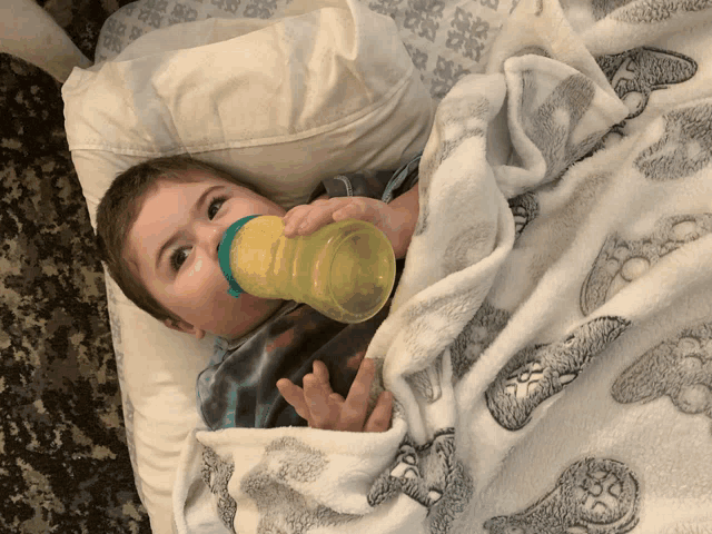 a baby drinking from a bottle while laying on a blanket