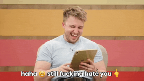 a man is laughing while looking at a tablet with the words " haha still fucking hate you " written below him