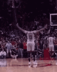 a basketball player with the number 13 on his jersey stands on the court with his arms outstretched