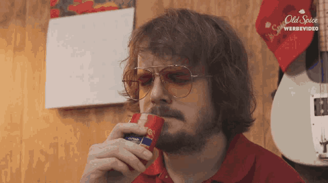 a man wearing sunglasses is drinking from a can that says old spice