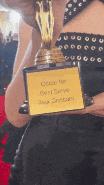 a woman holding an oscar for best serve alex consani trophy
