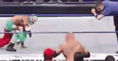 two wrestlers are fighting in a wrestling ring while a referee watches .