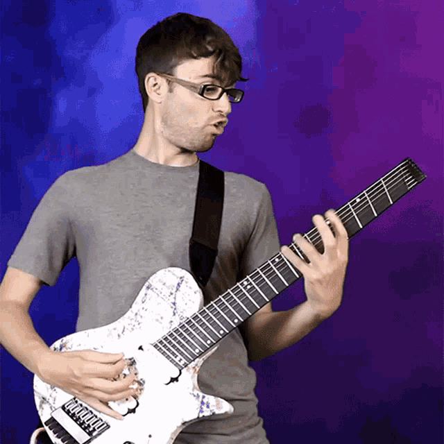 a man wearing glasses is playing a guitar with a purple background