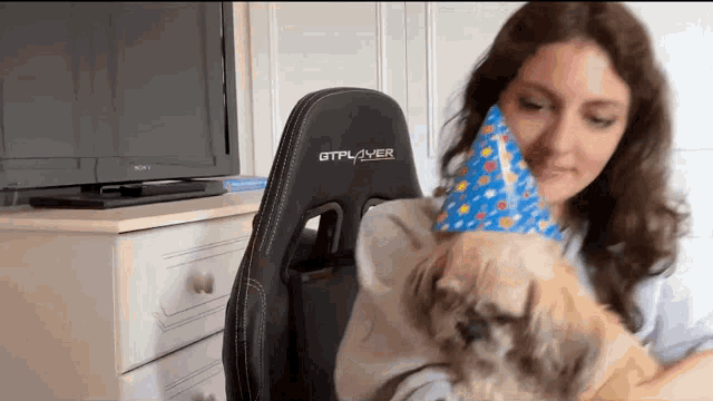 a woman wearing a gtplayer chair is holding a dog