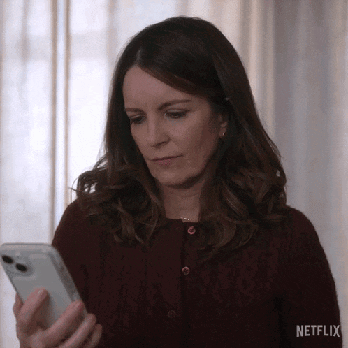 a woman in a red sweater is using a cell phone .