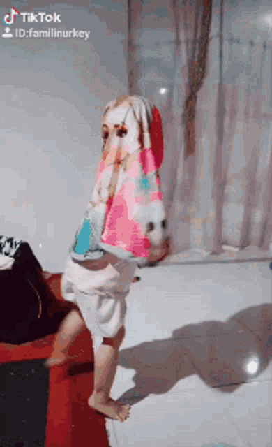 a tiktok video of a baby wrapped in a colorful blanket