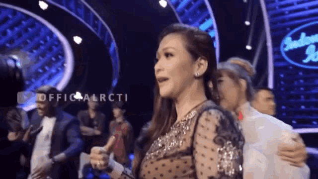 a woman is giving a thumbs up in front of a sign that says ' indonesian idol '