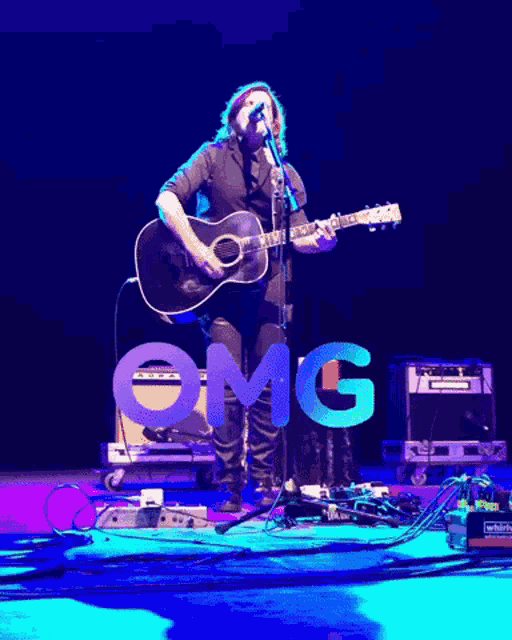 a man singing into a microphone while playing a guitar with the word omg in the background