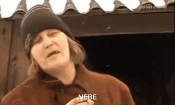 a woman wearing a beanie and a brown jacket says nebe in a foreign language