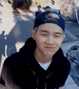 a young man wearing a baseball cap is smiling while standing on a road .