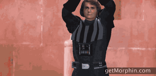 a man is holding a lightsaber in front of a red wall and the website getmorphin.com is visible in the corner