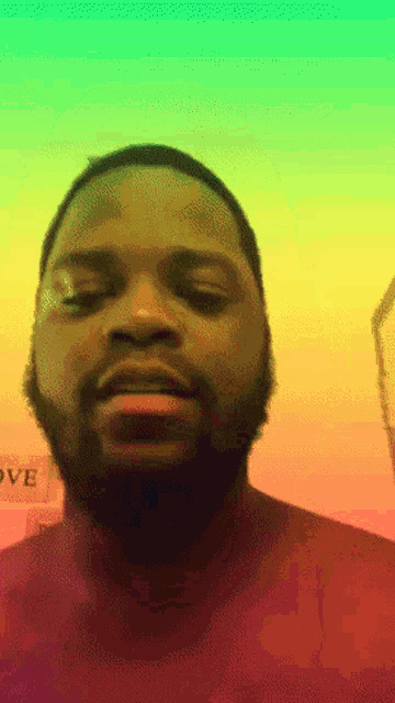 a man with a beard is looking at the camera with a sign in the background that says love