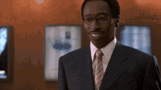 a man in a suit and tie is smiling in front of a wall .