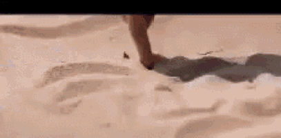 a woman is sitting on the beach with her legs crossed and her feet in the sand .