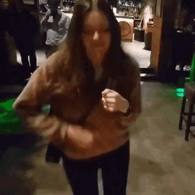 a woman is dancing in a dark room with a green light in the background