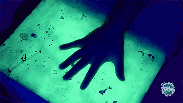 a person 's hand is glowing in the dark on a glowing surface
