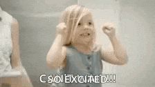a little girl is dancing in front of a mirror with the words `` c so excited '' written on the bottom .