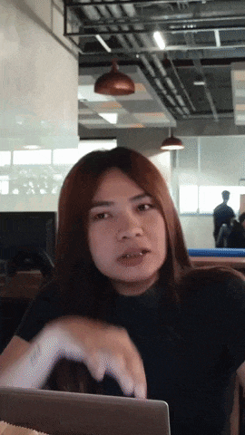 a woman in a black shirt is sitting in front of a laptop and making a funny face